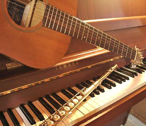 Classical guitar and flute resting on a piano, ready for a lesson