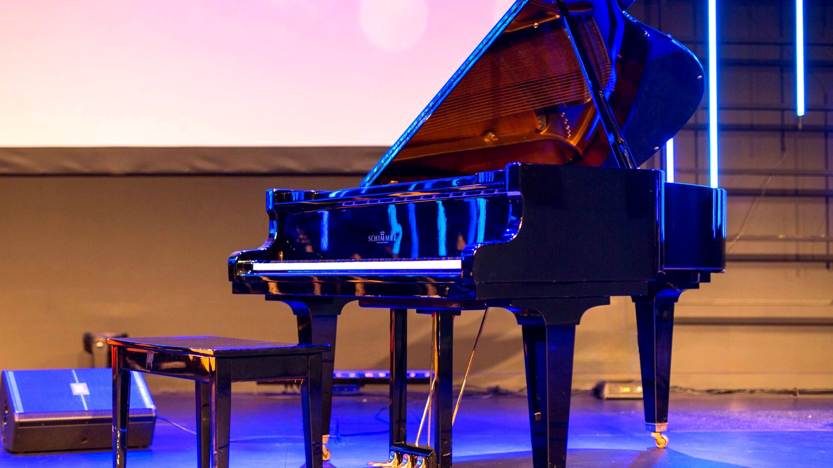 Schimmel grand piano on stage under blue lighting